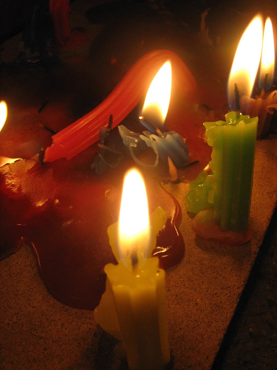 Candele rituali colorate accese, con la cera fusa sulla pietra